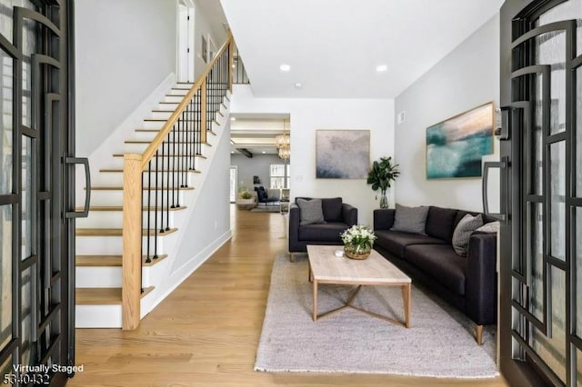 living room featuring stairs, recessed lighting, baseboards, and wood finished floors