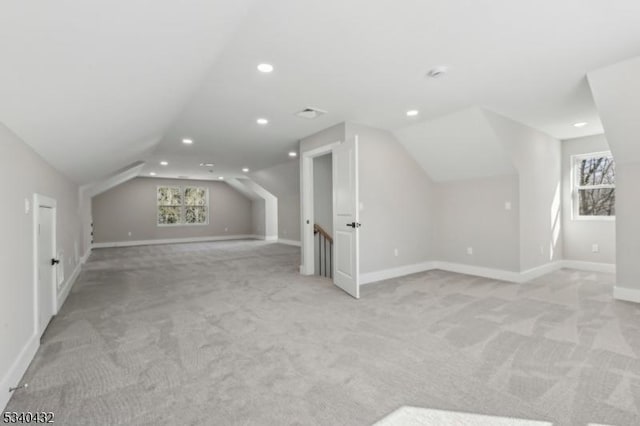 bonus room with lofted ceiling, a healthy amount of sunlight, baseboards, and light colored carpet