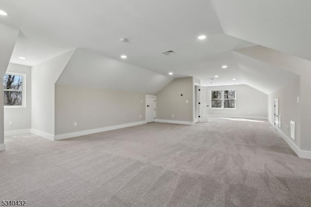 bonus room with light colored carpet, visible vents, vaulted ceiling, and baseboards