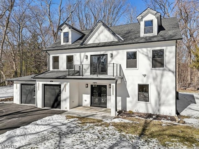 view of front of house with a balcony, stucco siding, driveway, and french doors