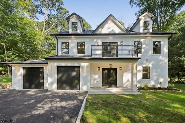 view of front of house featuring driveway, french doors, a front lawn, and a balcony