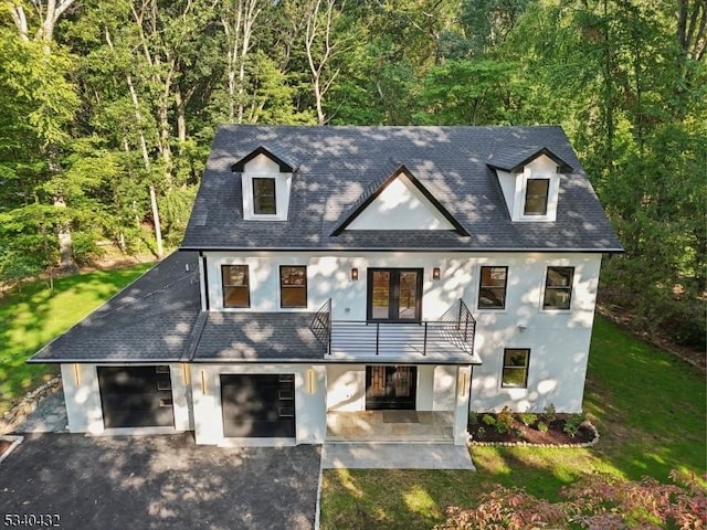 view of front of home featuring a patio, an attached garage, driveway, french doors, and a front yard