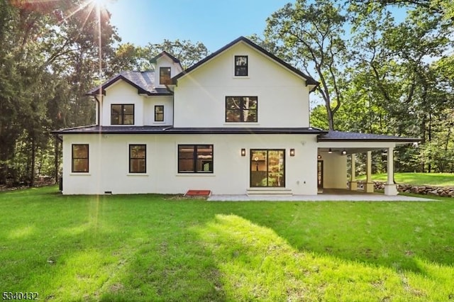 rear view of property featuring a lawn, a patio area, and stucco siding