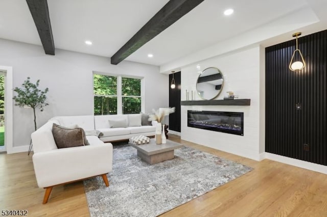 living room with recessed lighting, wood finished floors, beam ceiling, and a glass covered fireplace