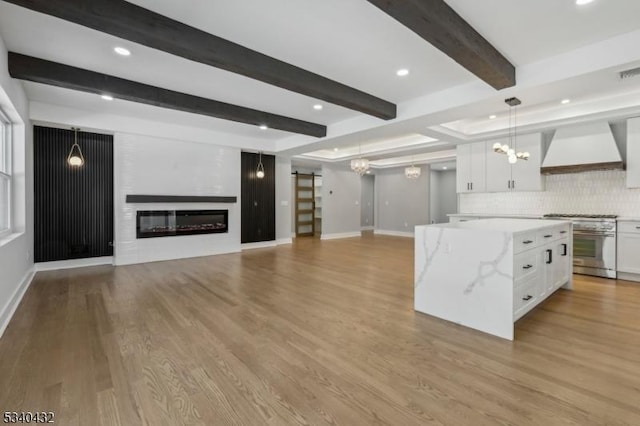 kitchen featuring a glass covered fireplace, high end range, a center island, premium range hood, and white cabinetry