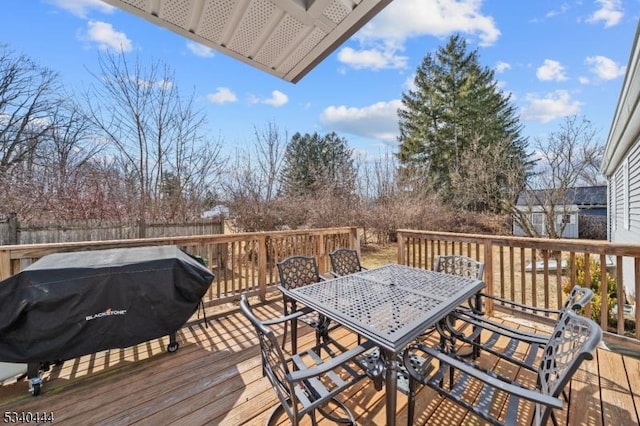 wooden deck with outdoor dining area, fence, and grilling area