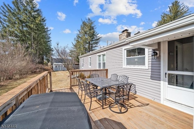 wooden deck featuring an outbuilding, a shed, and outdoor dining space