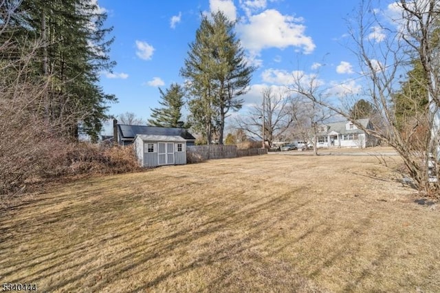 view of yard with an outbuilding, a shed, and fence