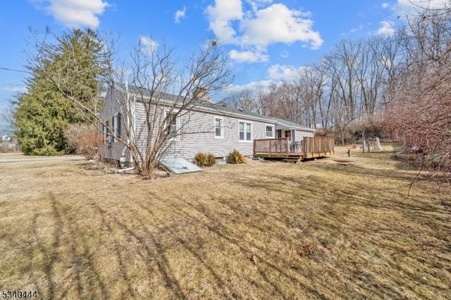 view of home's exterior featuring a deck, a chimney, and a lawn