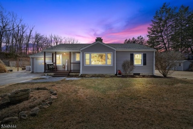 single story home with aphalt driveway, a chimney, covered porch, a front yard, and a garage