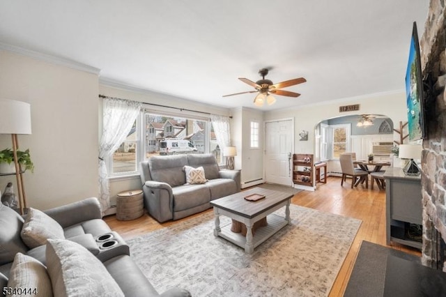 living room featuring arched walkways, light wood-style flooring, ceiling fan, crown molding, and a baseboard heating unit