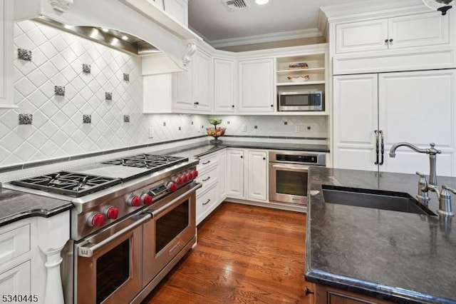 kitchen with built in appliances, white cabinets, custom range hood, and ornamental molding