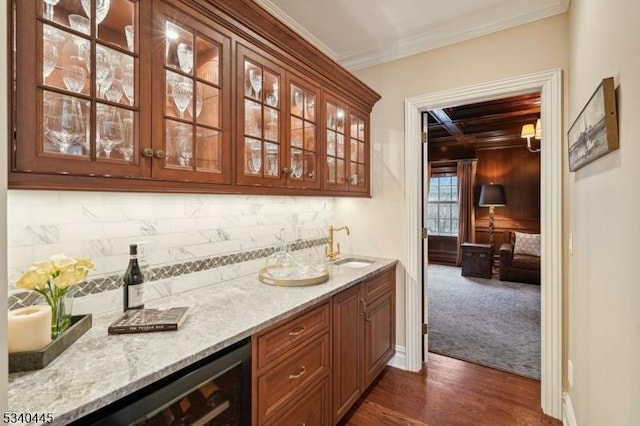 bar featuring beverage cooler, ornamental molding, tasteful backsplash, wet bar, and dark wood-style flooring