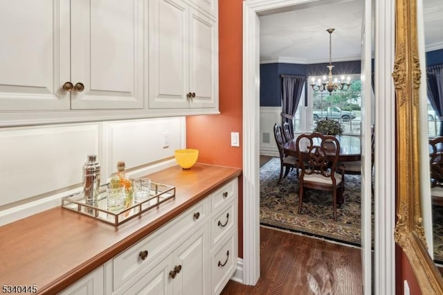 kitchen featuring pendant lighting, ornamental molding, an inviting chandelier, dark wood-style floors, and white cabinets