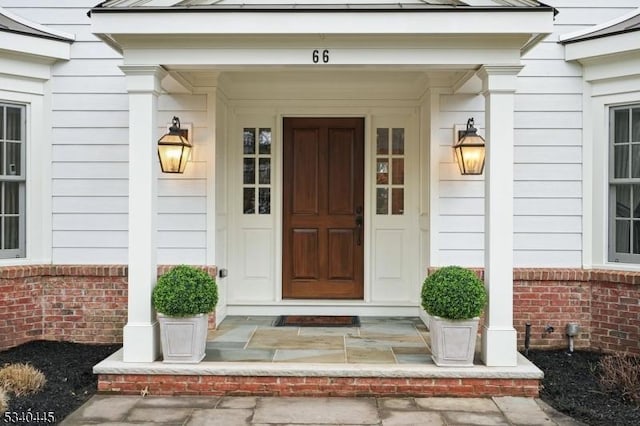 view of exterior entry featuring brick siding and covered porch