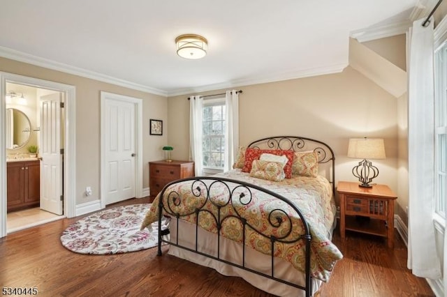 bedroom with connected bathroom, baseboards, wood finished floors, and crown molding