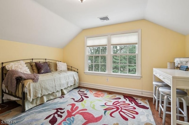 bedroom with visible vents, baseboards, wood finished floors, and vaulted ceiling