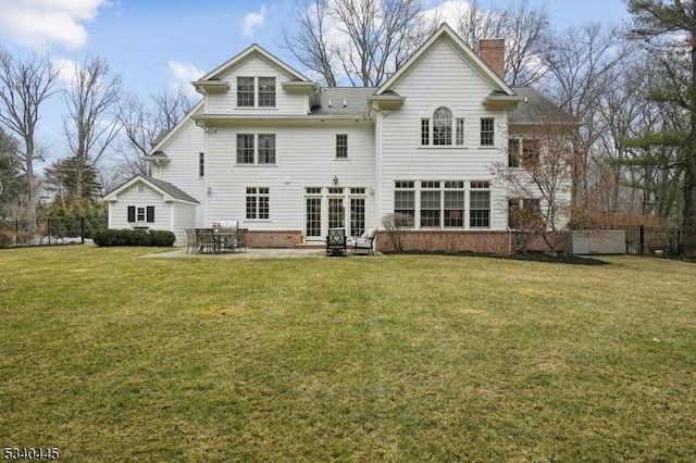 rear view of property featuring a yard, a patio area, a chimney, and fence