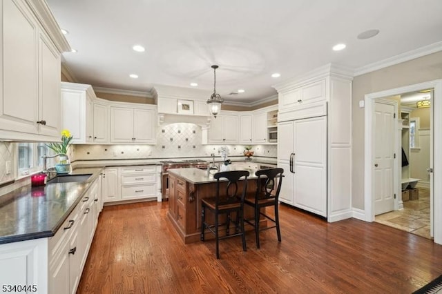 kitchen with high quality appliances, dark countertops, a breakfast bar, and white cabinets