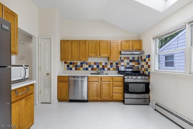 kitchen featuring vaulted ceiling with skylight, a baseboard radiator, appliances with stainless steel finishes, light countertops, and under cabinet range hood