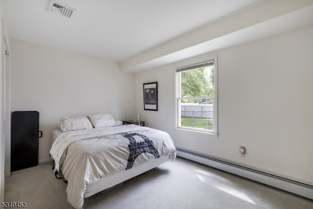 bedroom with a baseboard radiator, visible vents, and light colored carpet