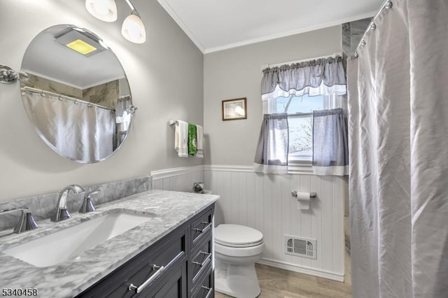 full bathroom with visible vents, wainscoting, toilet, ornamental molding, and vanity