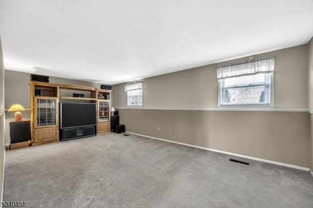 unfurnished living room featuring baseboards, visible vents, and carpet flooring