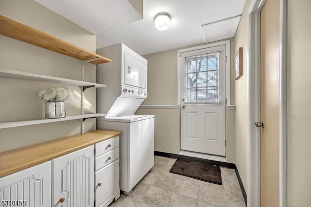 washroom featuring stacked washer and clothes dryer and baseboards