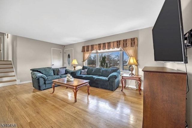 living room with light wood-style flooring, stairway, and baseboards