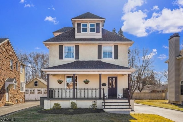 traditional style home with roof with shingles, covered porch, fence, cooling unit, and stucco siding