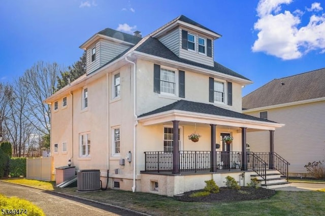 american foursquare style home with covered porch, stucco siding, and central AC unit