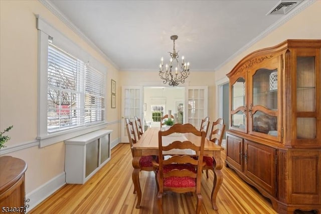 dining area featuring baseboards, visible vents, crown molding, light wood-type flooring, and a notable chandelier