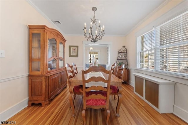 dining room featuring a chandelier, ornamental molding, light wood-type flooring, and visible vents