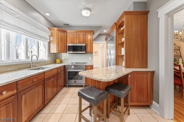 kitchen featuring tasteful backsplash, visible vents, appliances with stainless steel finishes, a peninsula, and a sink