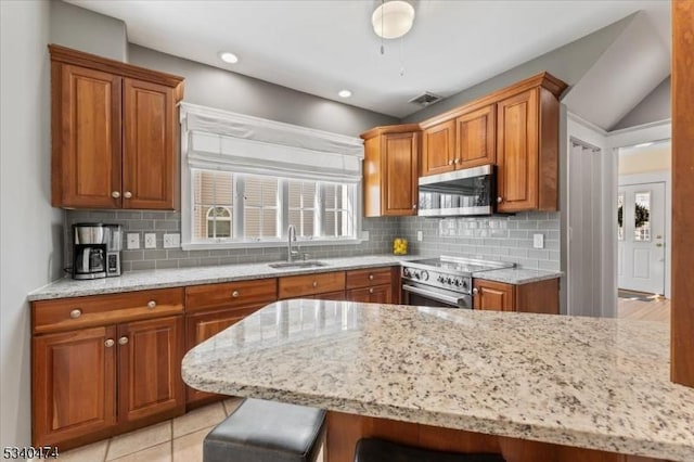 kitchen with visible vents, a breakfast bar area, appliances with stainless steel finishes, brown cabinets, and a sink