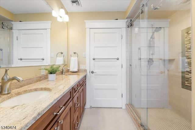 full bath with double vanity, a shower stall, visible vents, and a sink