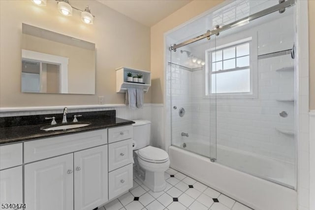 full bathroom with wainscoting, vanity, toilet, and combined bath / shower with glass door