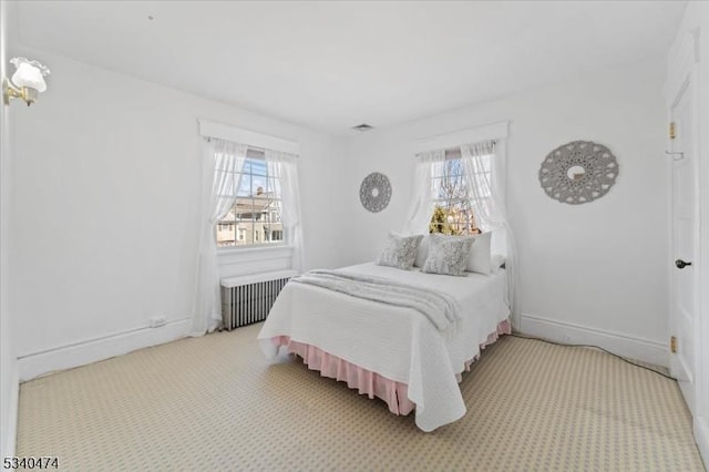 carpeted bedroom featuring radiator, multiple windows, and baseboards