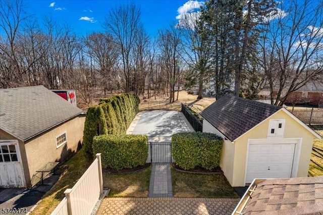 exterior space featuring a garage, fence, and an outbuilding