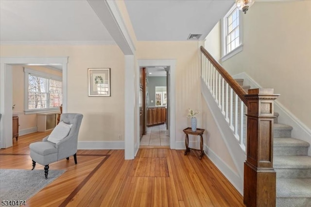 interior space featuring stairs, light wood-type flooring, visible vents, and baseboards