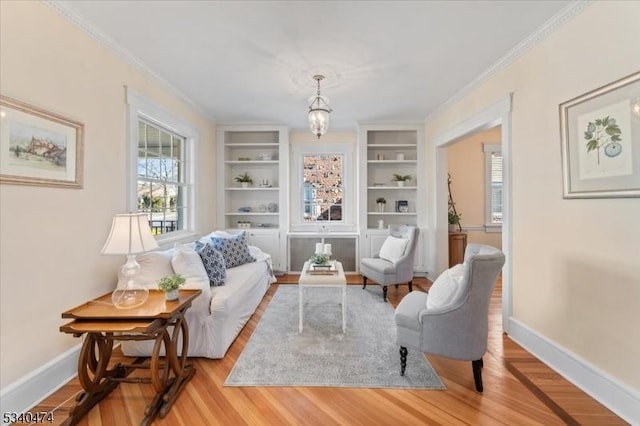 sitting room with light wood-style floors, crown molding, and baseboards