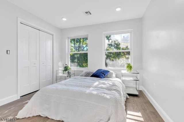 bedroom featuring recessed lighting, wood finished floors, visible vents, baseboards, and a closet