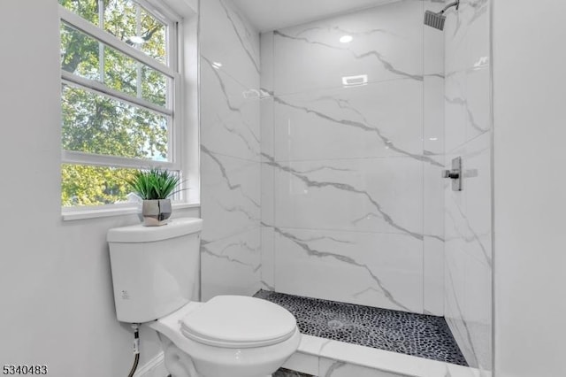 bathroom with toilet, marble finish floor, a marble finish shower, and a wealth of natural light