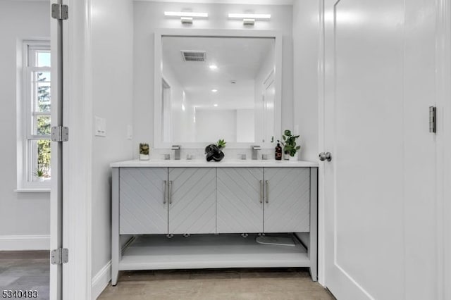 full bathroom with double vanity, a sink, visible vents, and baseboards