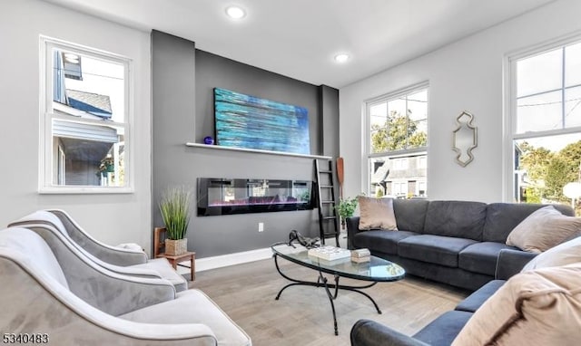 living area with a glass covered fireplace, recessed lighting, baseboards, and wood finished floors