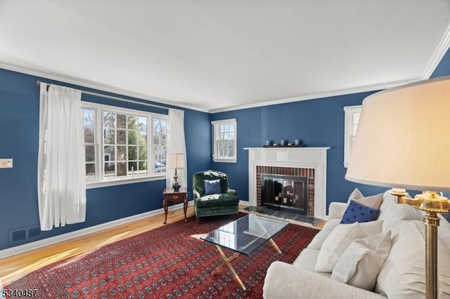 living area with a fireplace, wood finished floors, and crown molding