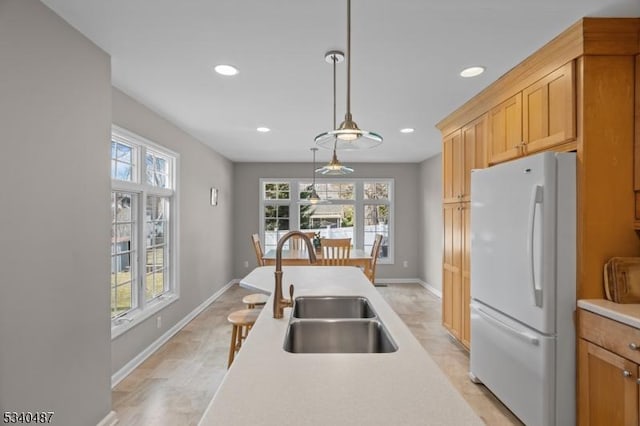 kitchen with recessed lighting, a sink, light countertops, freestanding refrigerator, and decorative light fixtures