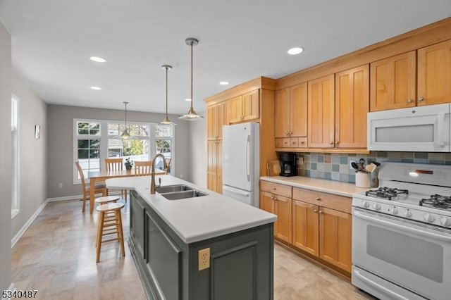 kitchen with a kitchen island with sink, white appliances, a sink, light countertops, and backsplash