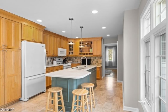 kitchen with a breakfast bar area, open shelves, light countertops, a sink, and white appliances