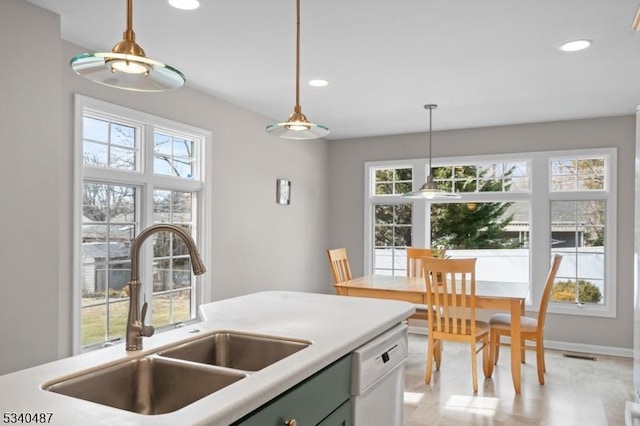 kitchen with hanging light fixtures, white dishwasher, a sink, and visible vents